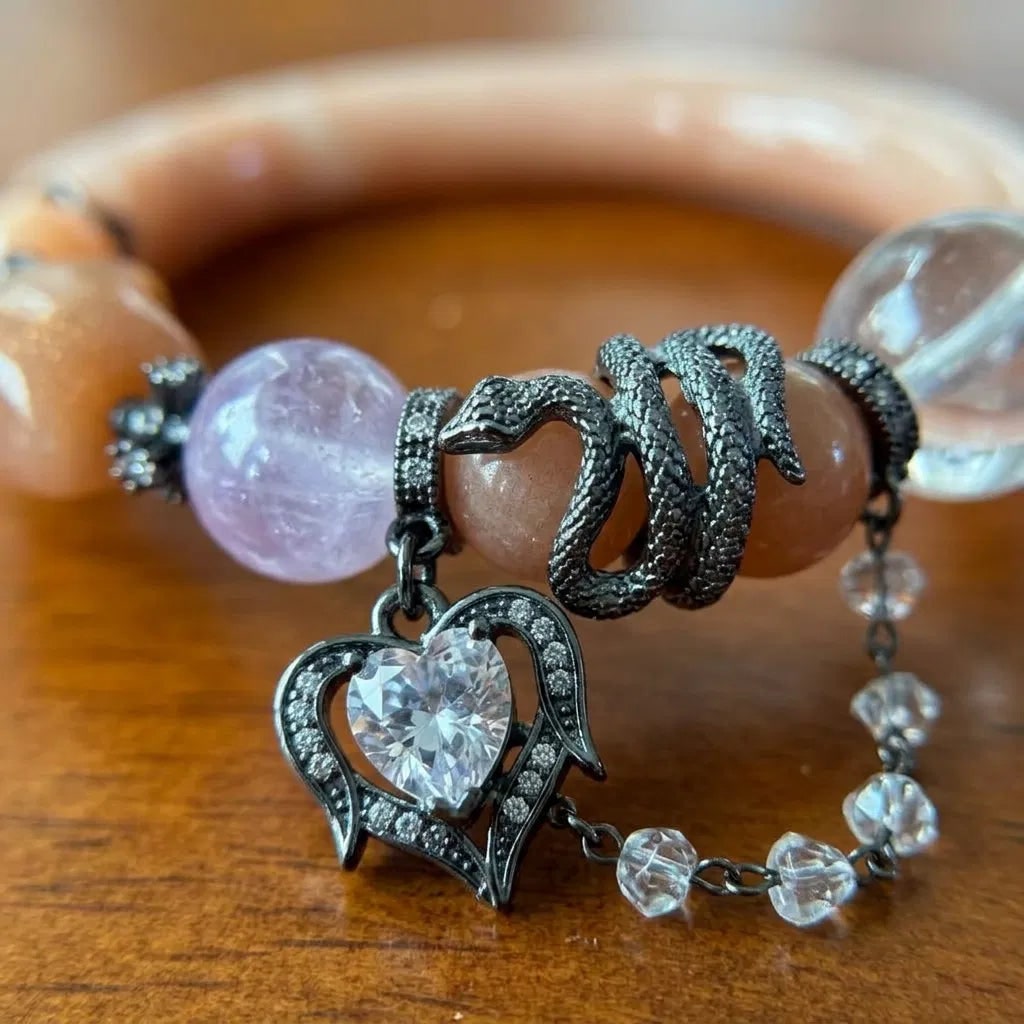 Peach moonstone, clear quartz, and amethyst snake bangle worn on a wrist