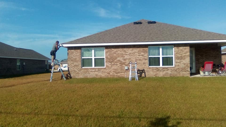 Crown & Cross installing seamless gutters along a brick home