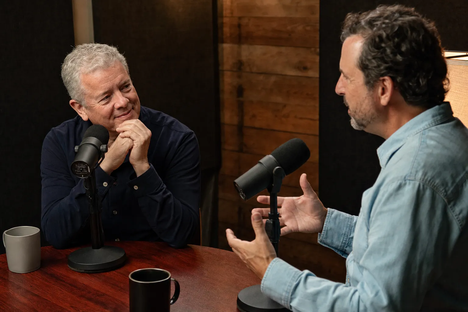 Two podcast guests listening closely during a friendly recording conversation