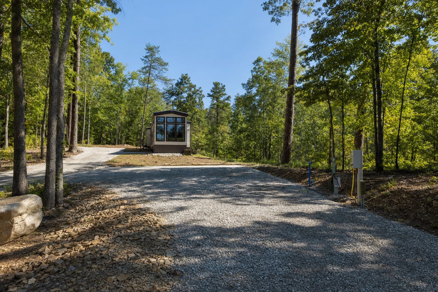 Prepared park model site with gravel pad, utility connections and clear delivery approach