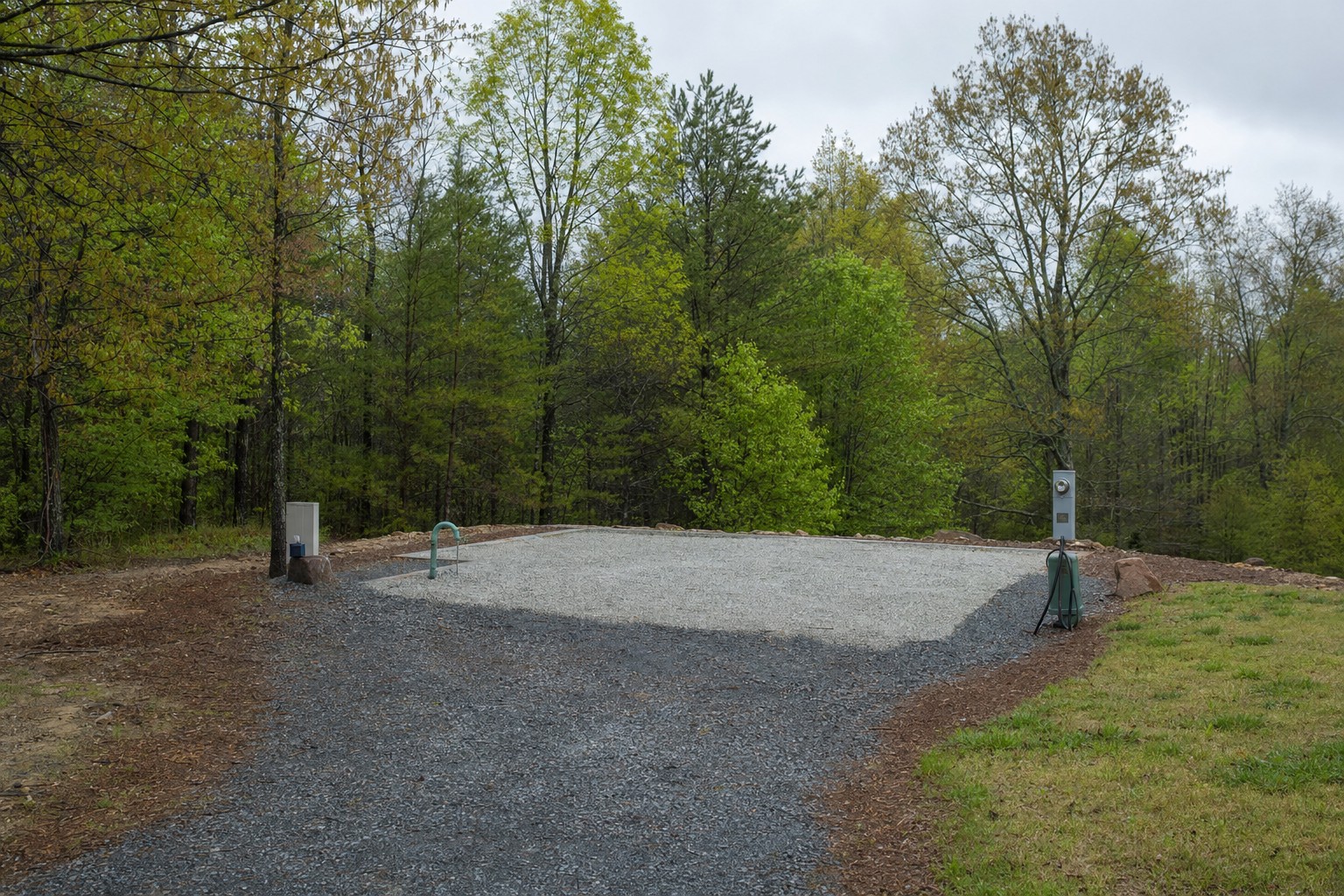 Prepared gravel park model site with utility connections and a clear approach