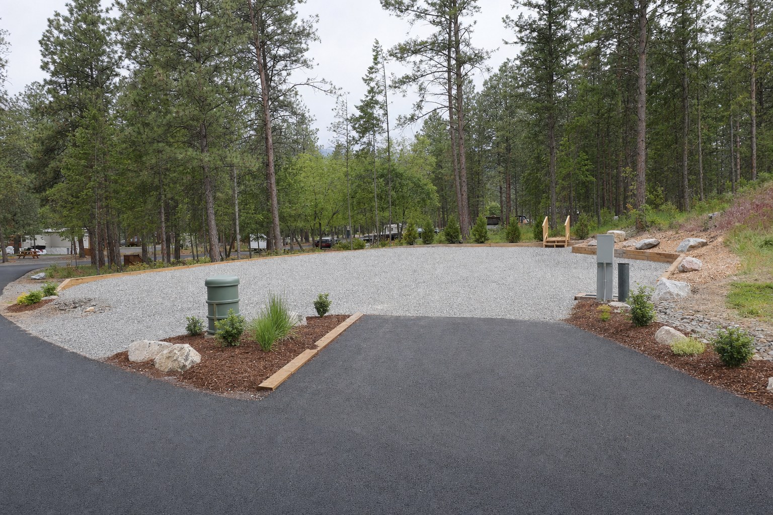 Prepared gravel park model site with utility connections and a clear driveway approach