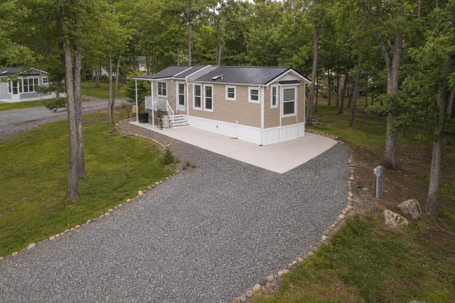 Prepared wooded RV site with a clear gravel approach and utility connection