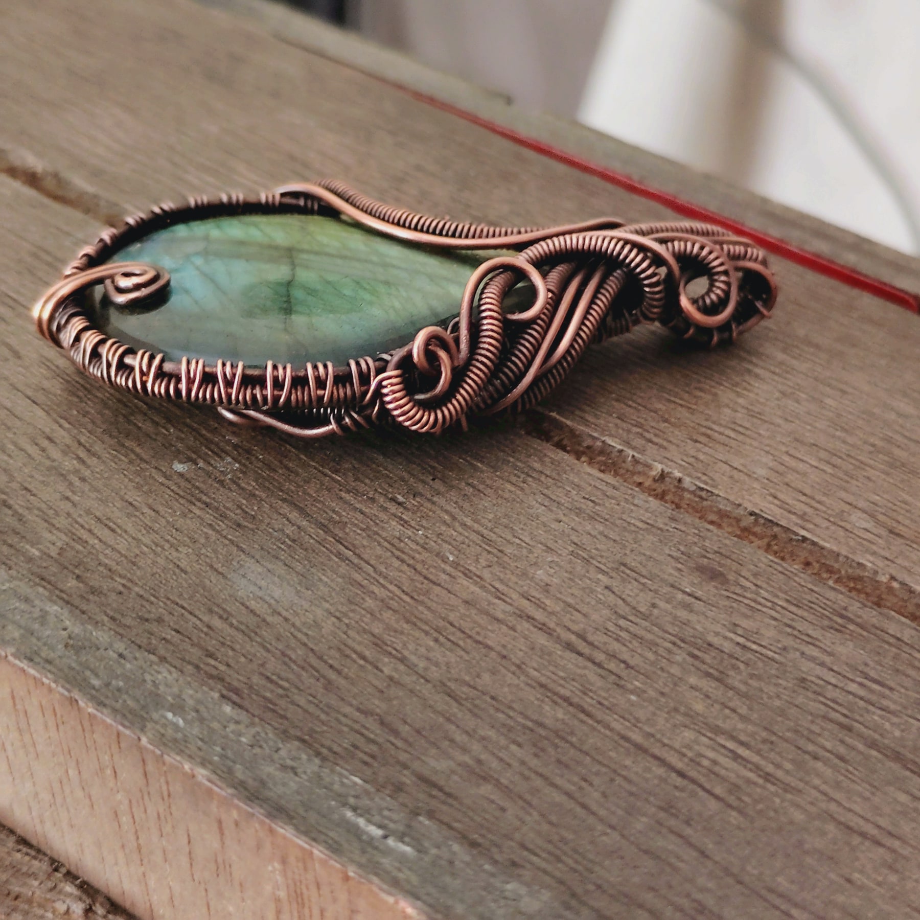 Labradorite pendant in oxidized copper wire wrap, shown at an angle