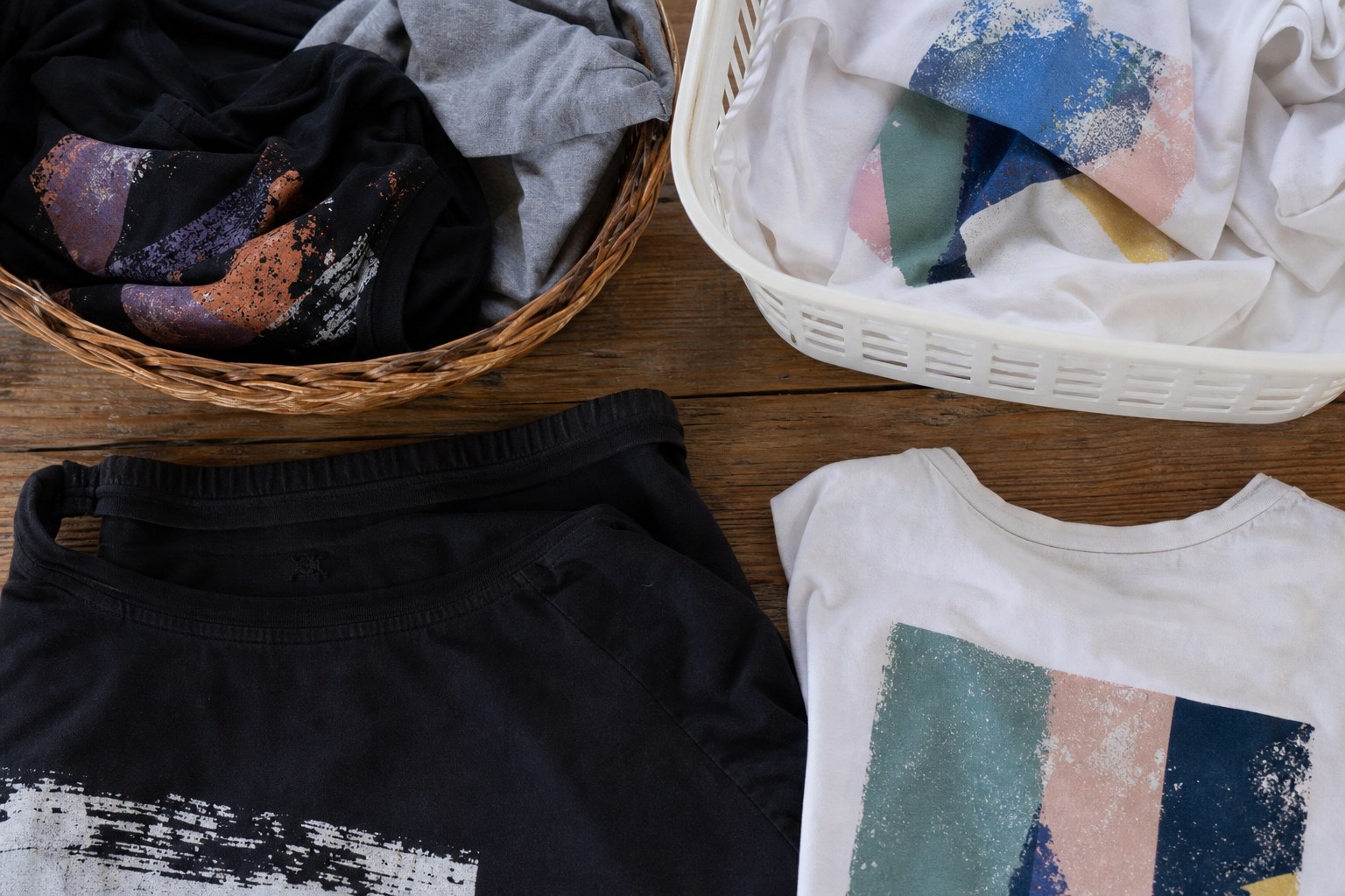 Dark and light graphic T-shirts sorted into separate laundry baskets