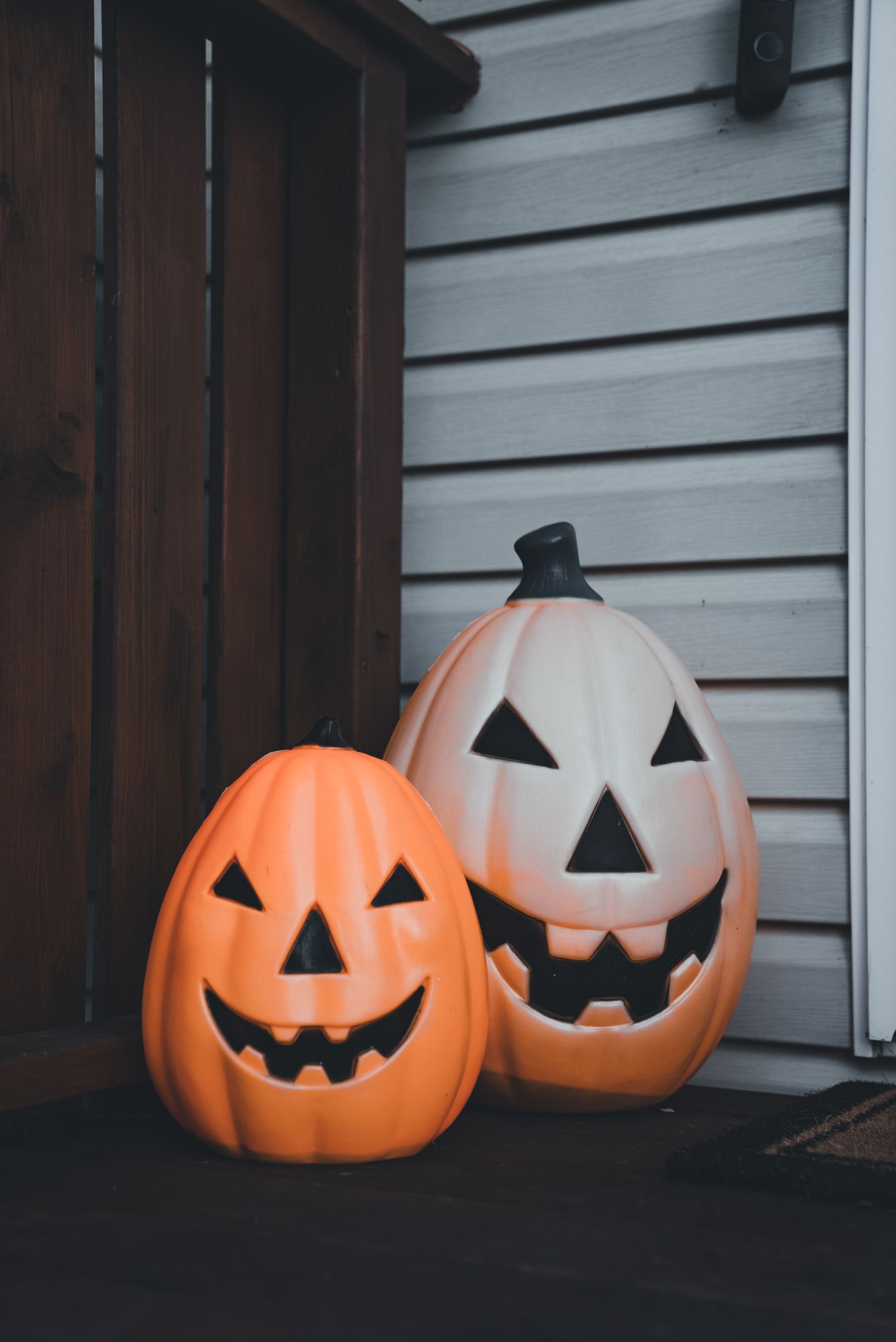 Two glowing jack-o-lantern decorations placed beside a front door