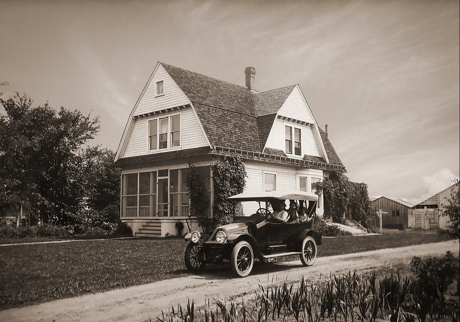 Historic photograph of a Victorian-era house with an early automobile in front