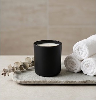 A hand-poured black container candle ready for its next burn.