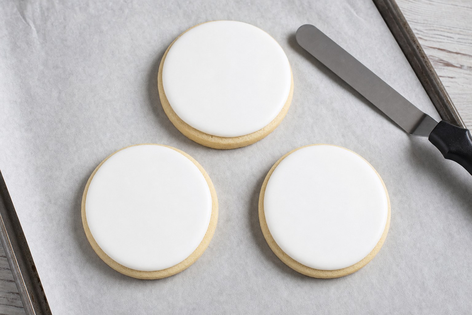 Three sugar cookies with smooth white royal icing ready for edible images