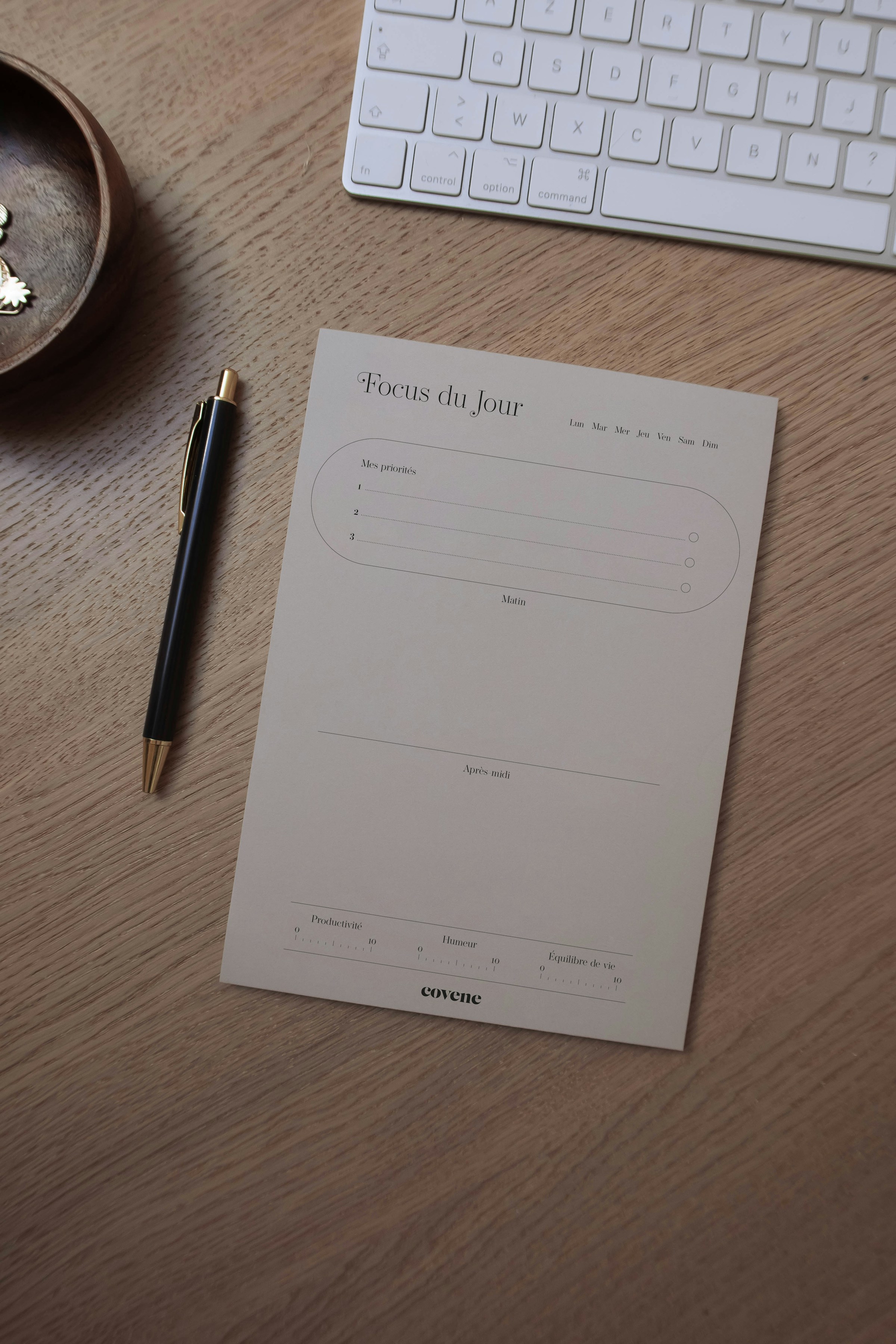 Weekly planner, pen, paper, and keyboard arranged on a desk