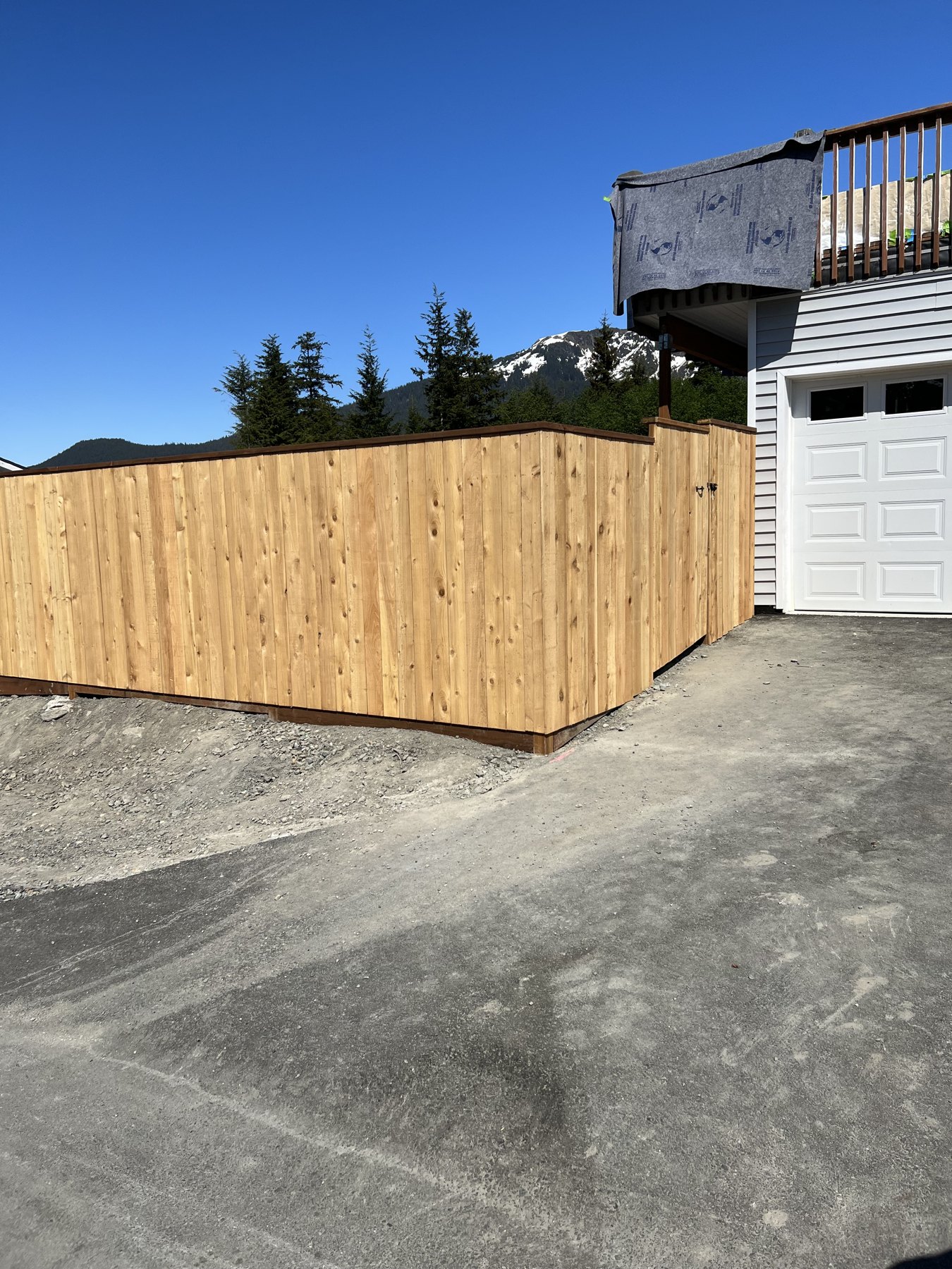 Completed wood privacy fence beside a driveway