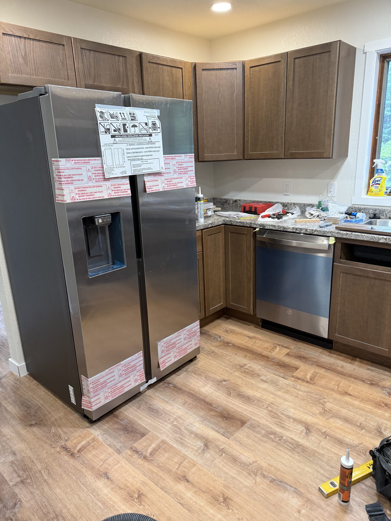 Kitchen renovation with wood cabinets, stainless steel appliances, and wood-look flooring
