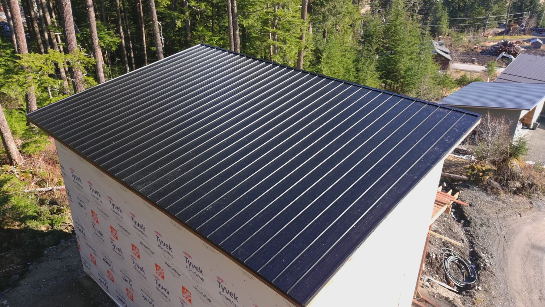 Completed dark metal roof surrounded by trees