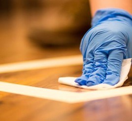 Gloved hand collecting a dust wipe sample from a finished floor