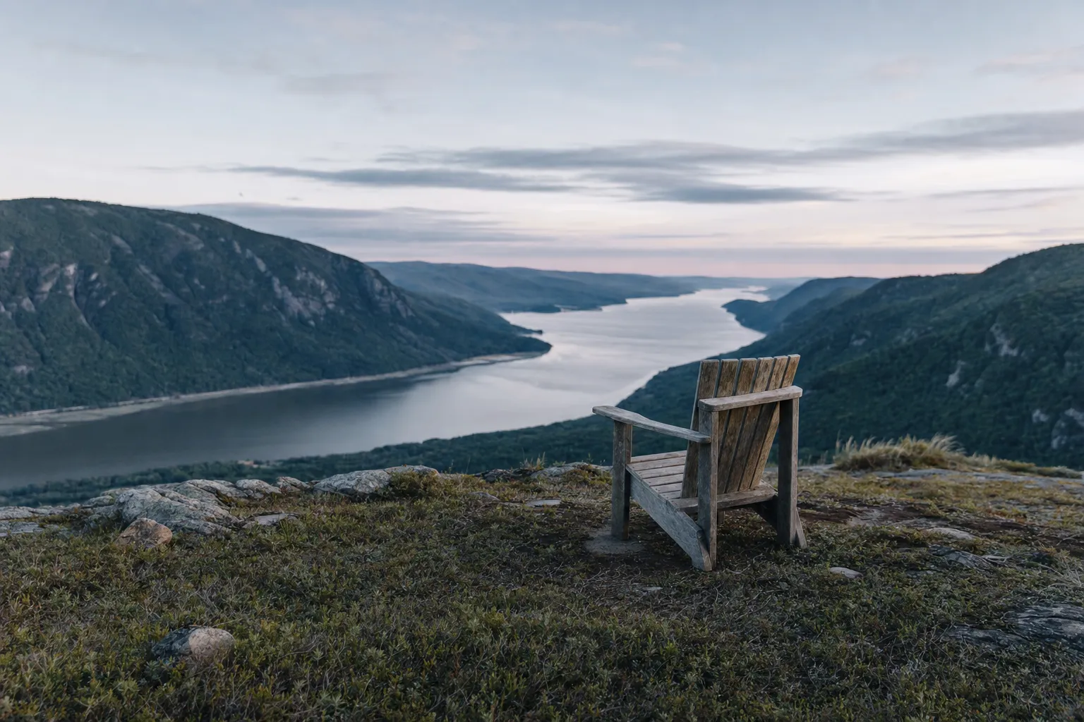 An empty chair looking over a wide river valley
