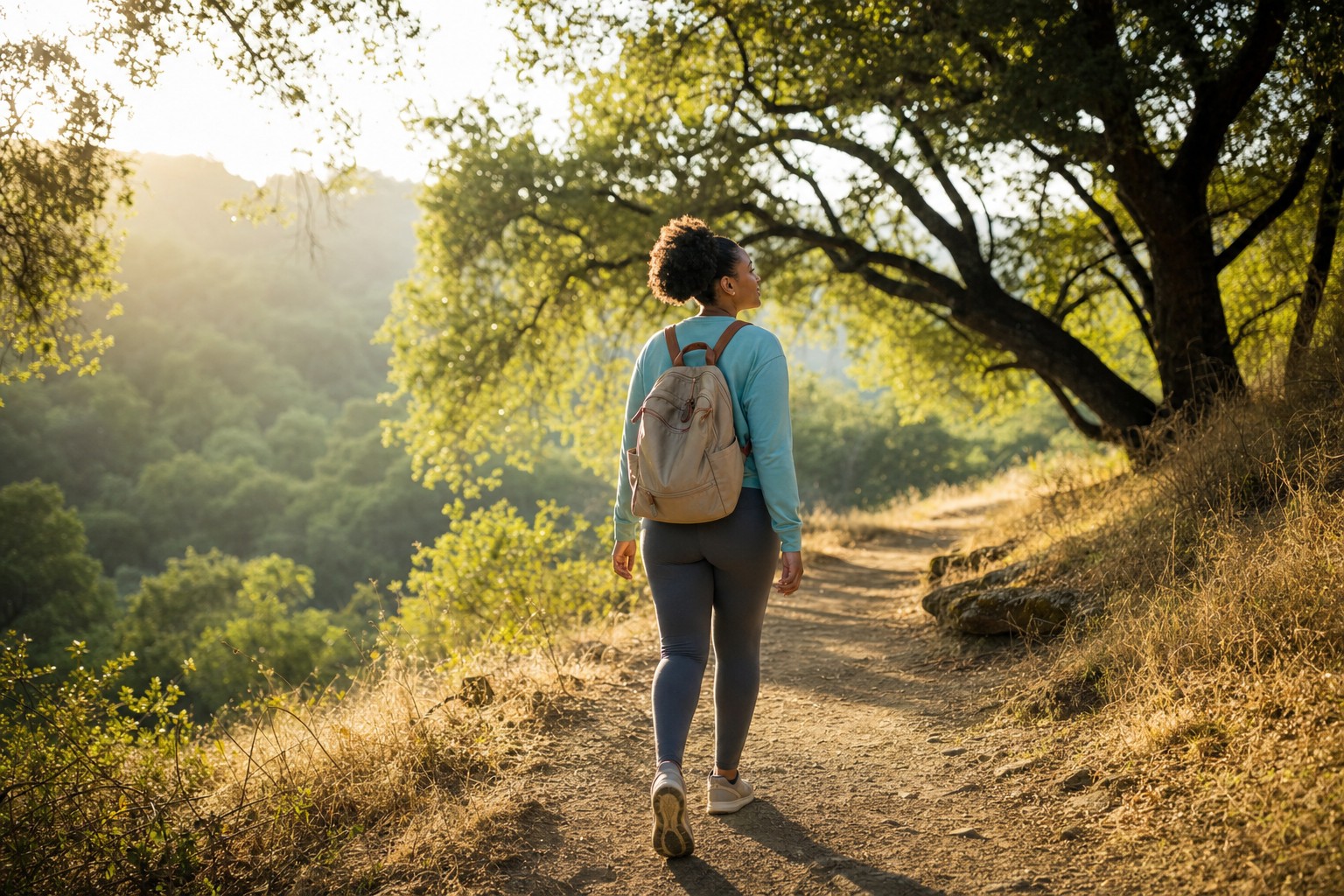 Woman walking thoughtfully through a sunlit oak trail