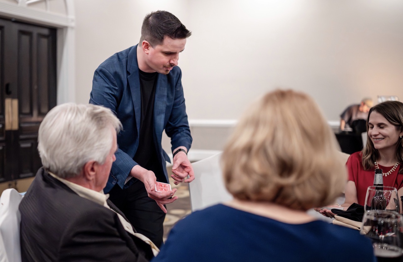 Neal Chamberlain performing close-up magic for guests at a formal event