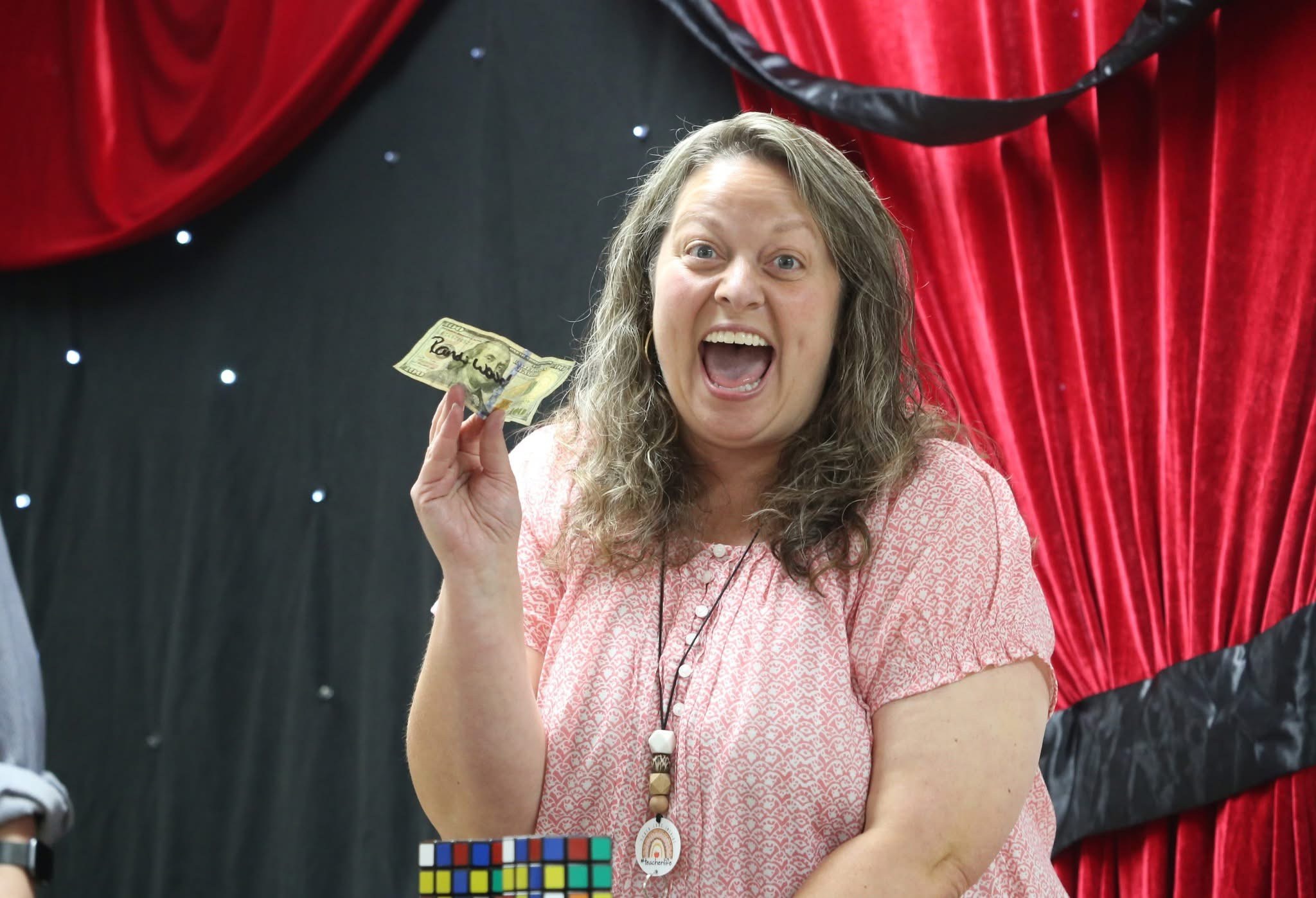 A smiling volunteer holding a $100 bill after a magic moment