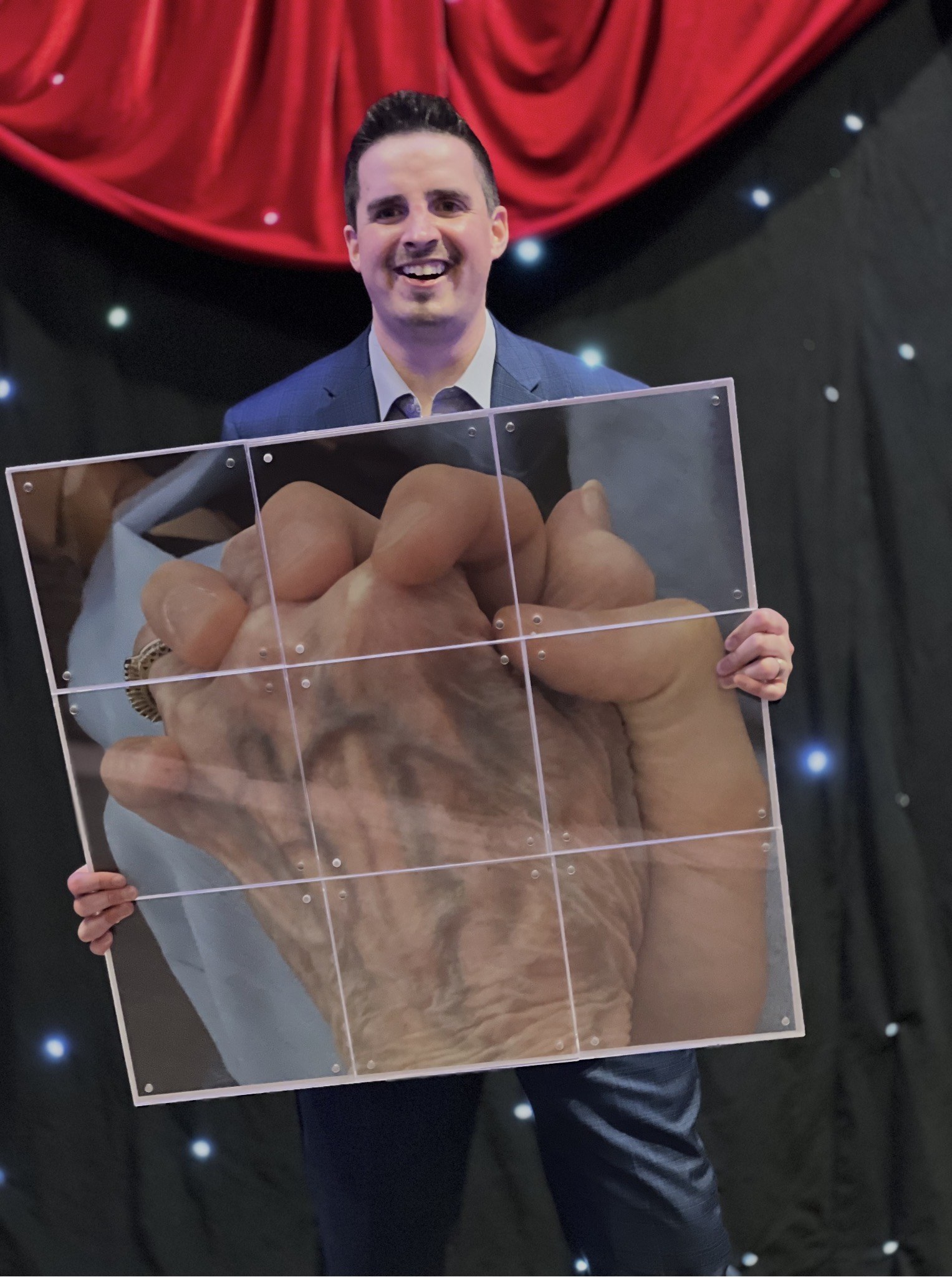 Neal Chamberlain holding a tribute image of his hand interlocked with his grandmother’s hand