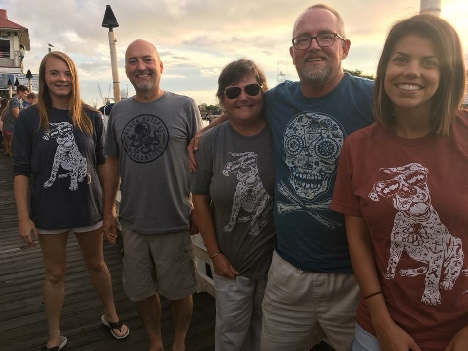 Five friends wearing Black Octopus shirts on a waterfront boardwalk