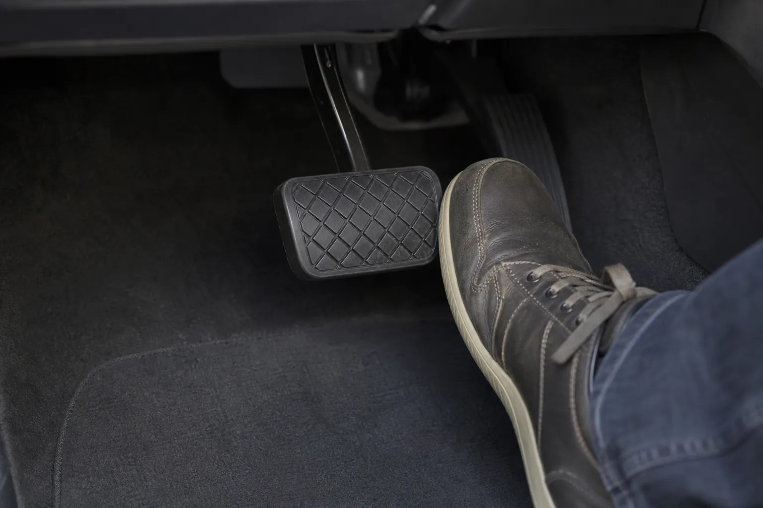 Driver's foot beside a vehicle brake pedal