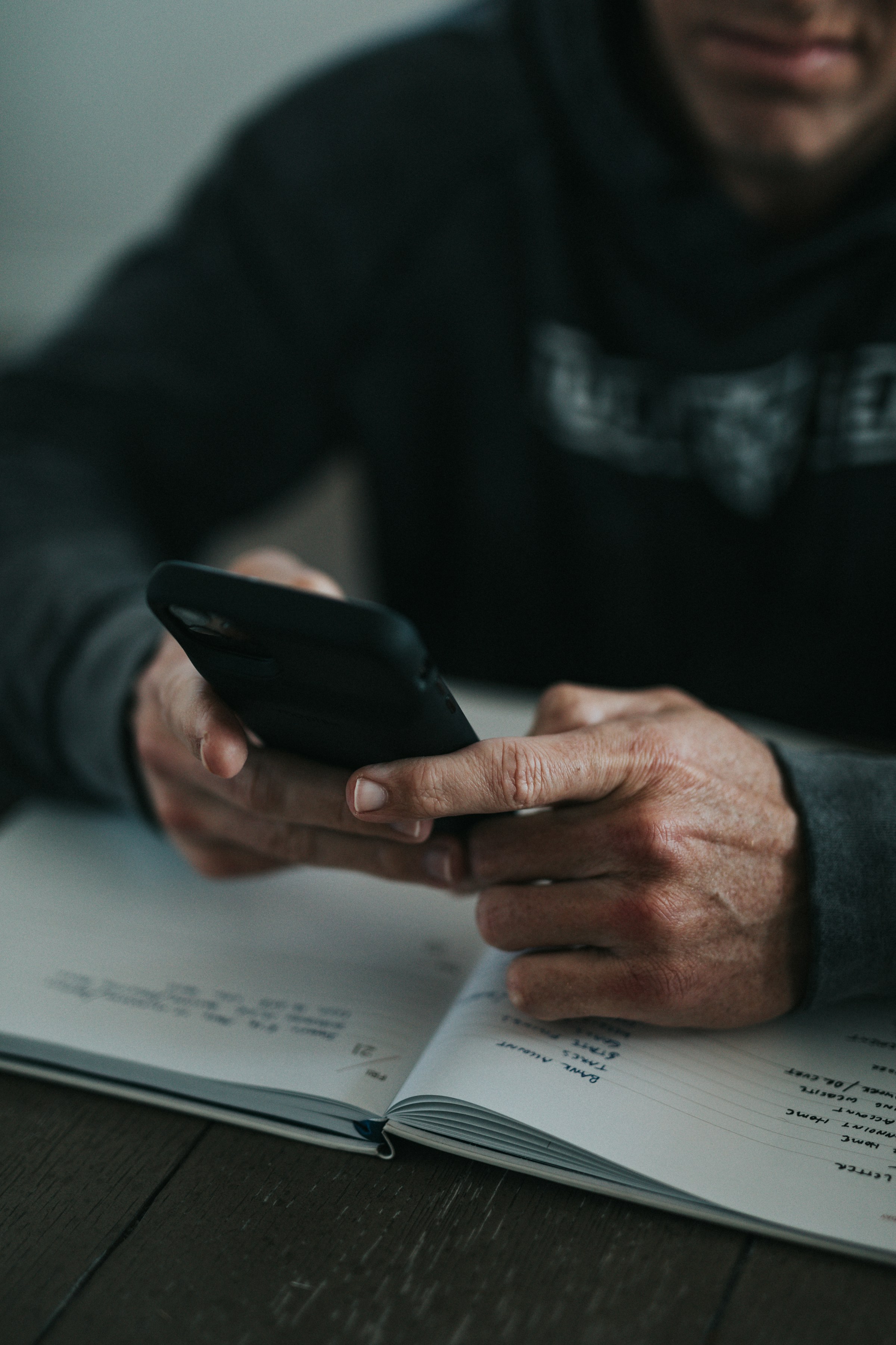 Hands holding a phone over an open notebook