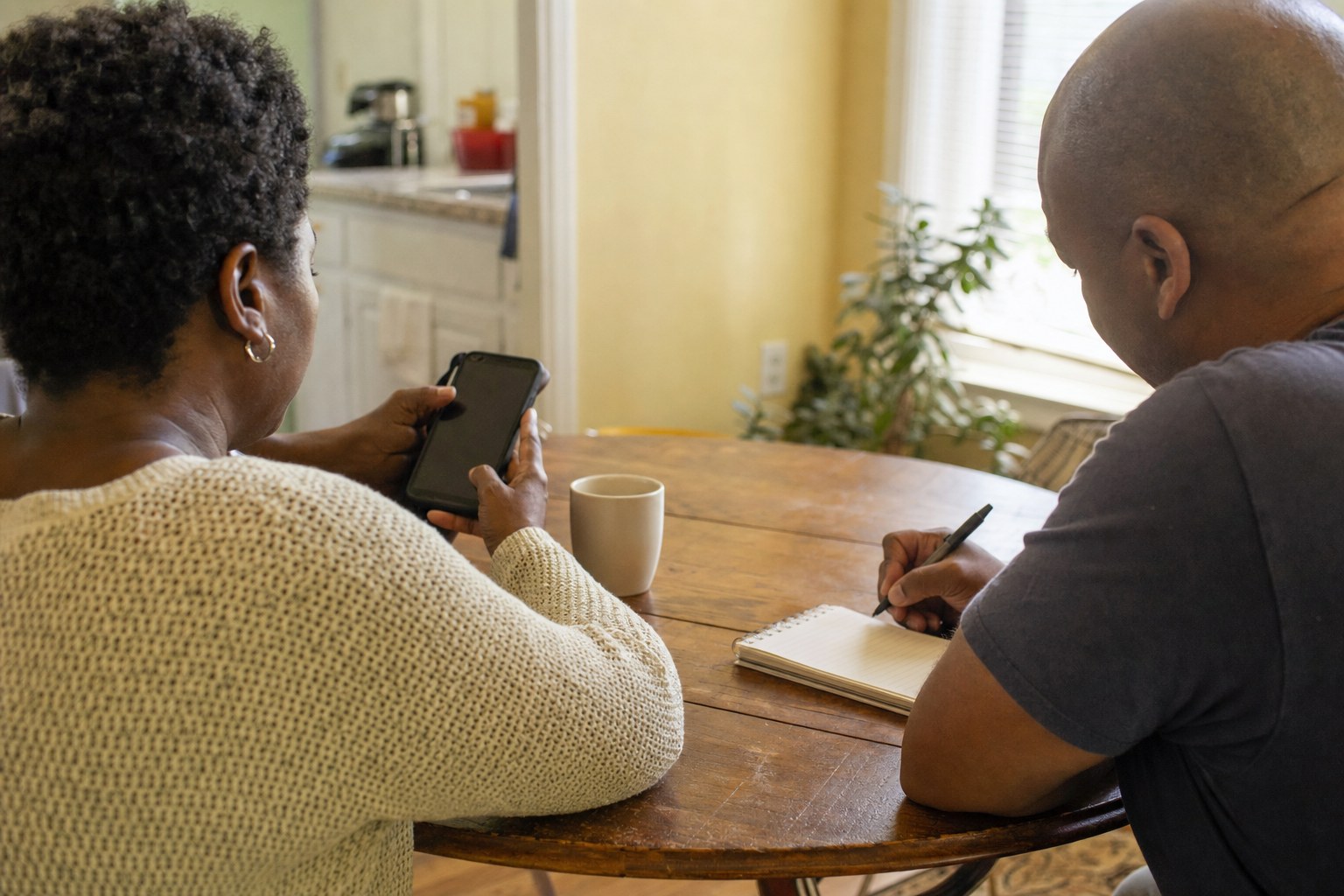 Two people quietly preparing a housing-support call at a kitchen table