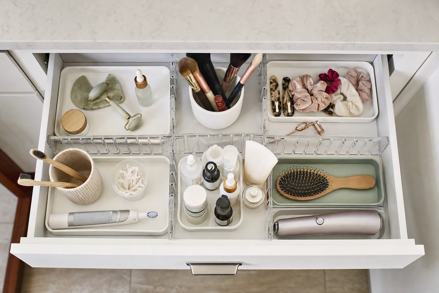 Bathroom vanity drawer organized with clear bins for makeup, hair accessories, and skin care
