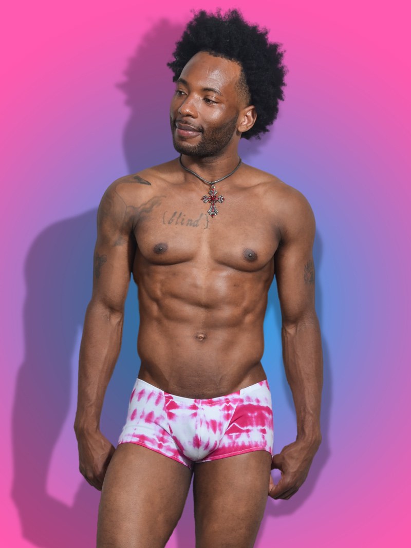 Model wearing pink tie-dye CecilAndEzra square cut swim trunks