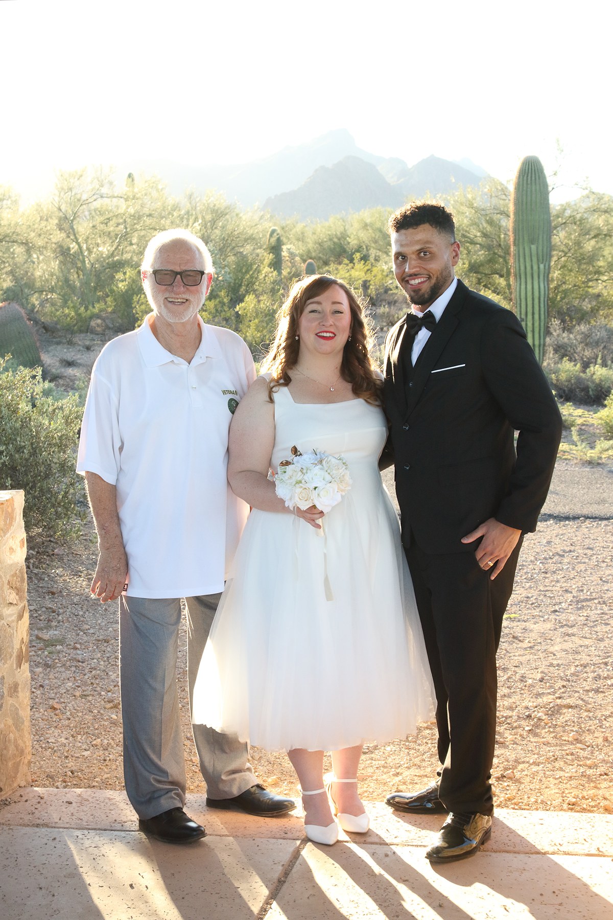 Newlyweds posing with Edward after their desert ceremony