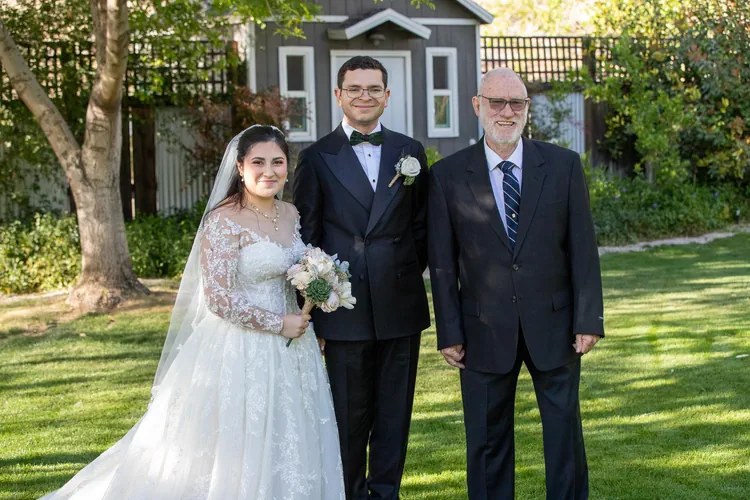 Edward with a newly married couple outdoors