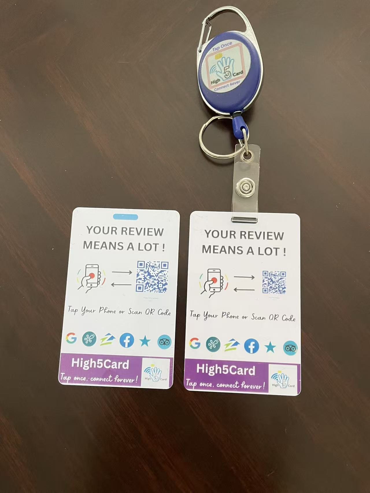 Two High5Card review tap cards on a table, with one attached to a blue badge reel