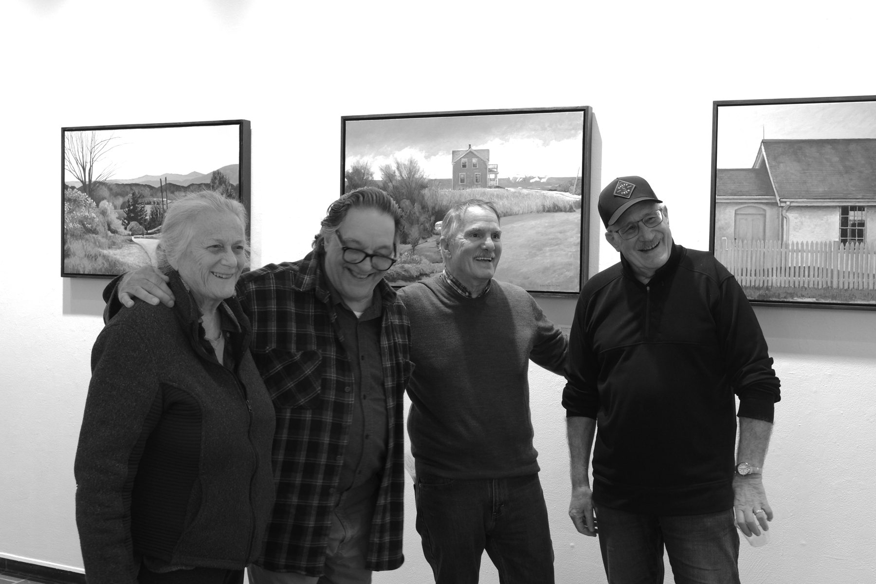 Guests posing together beside the exhibited paintings
