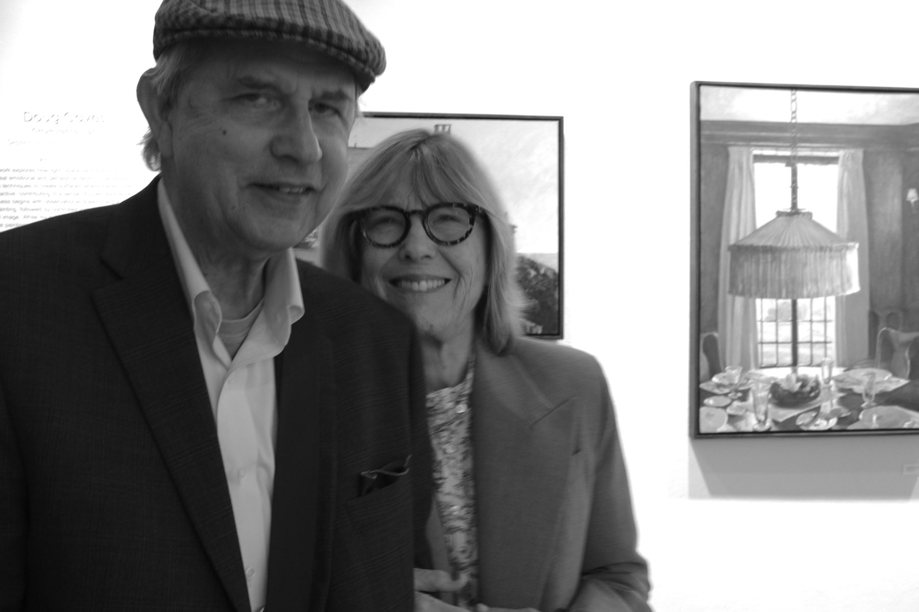Two visitors posing in front of a framed interior painting