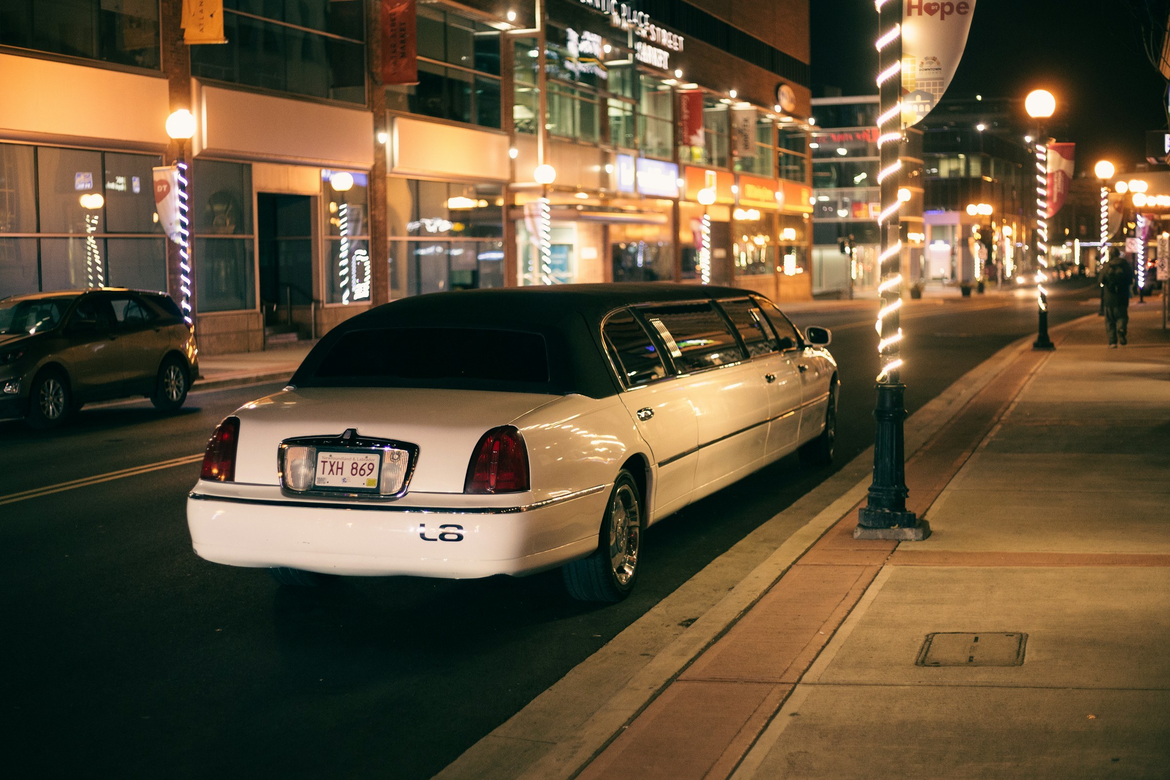 White stretch limousine parked under city lights at night
