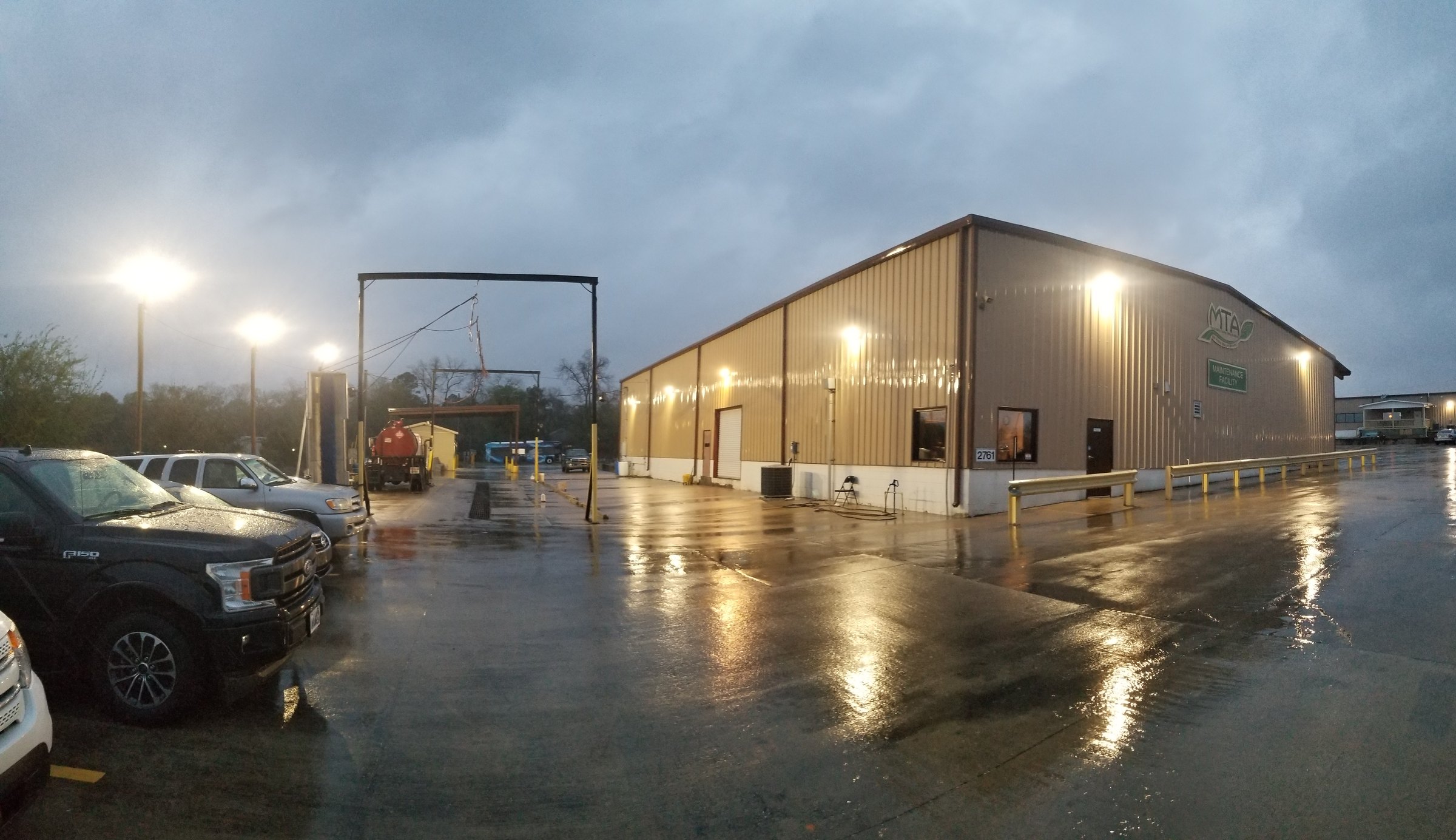 Commercial facility exterior with lighting and electrical infrastructure in wet weather