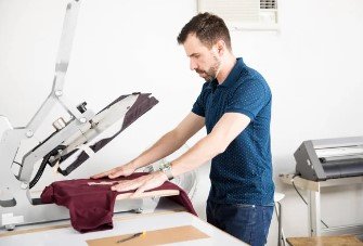 Person printing a maroon T-shirt