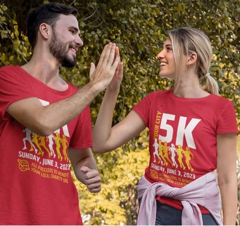 Two people wearing red 5K event T-shirts high-fiving outdoors