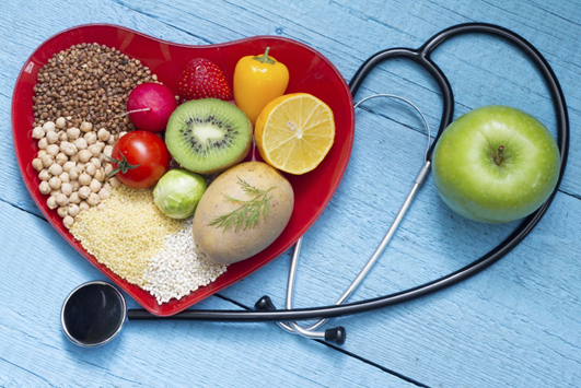 Nutritious foods arranged in a heart shape beside a stethoscope