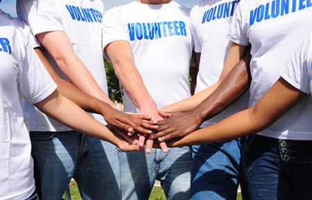 Volunteers joining hands while wearing volunteer shirts