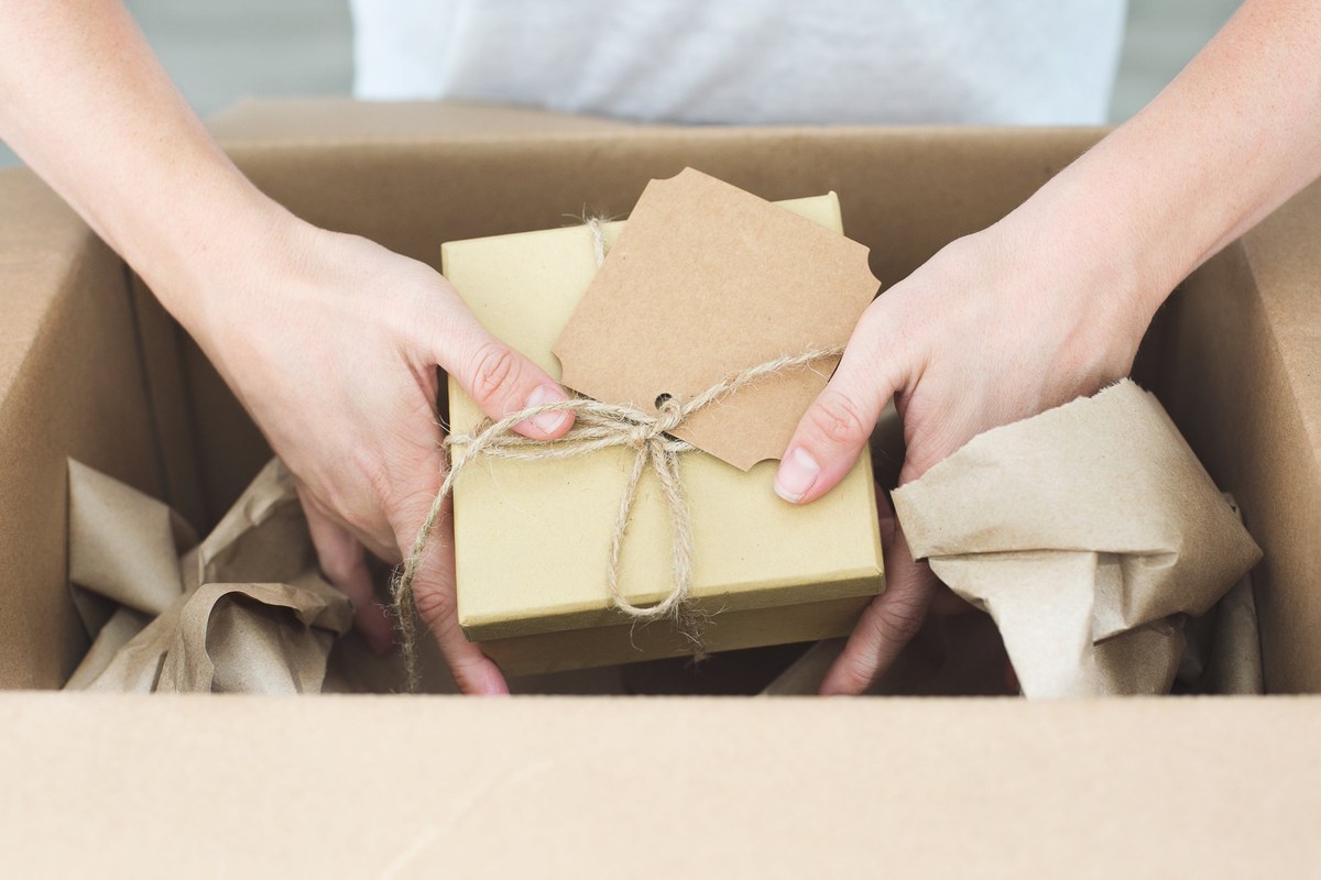 Hands packing a wrapped order into a shipping box