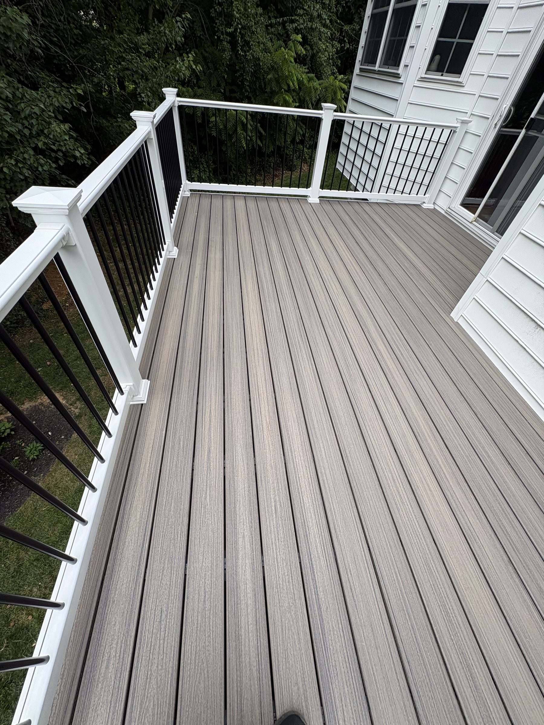 Gray deck boards with white posts and black railing balusters