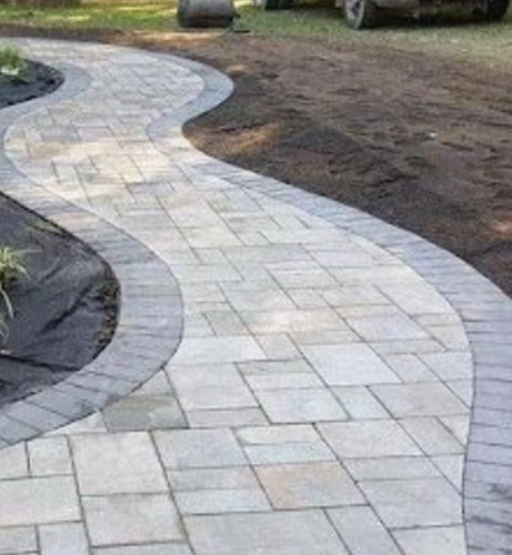 Curved gray paver walkway beside a home