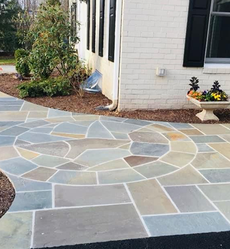 Flagstone entry patio and steps beside a white brick home