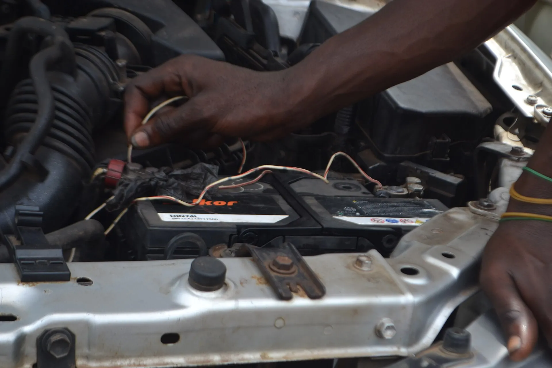 Mechanic testing a car battery at an open hood