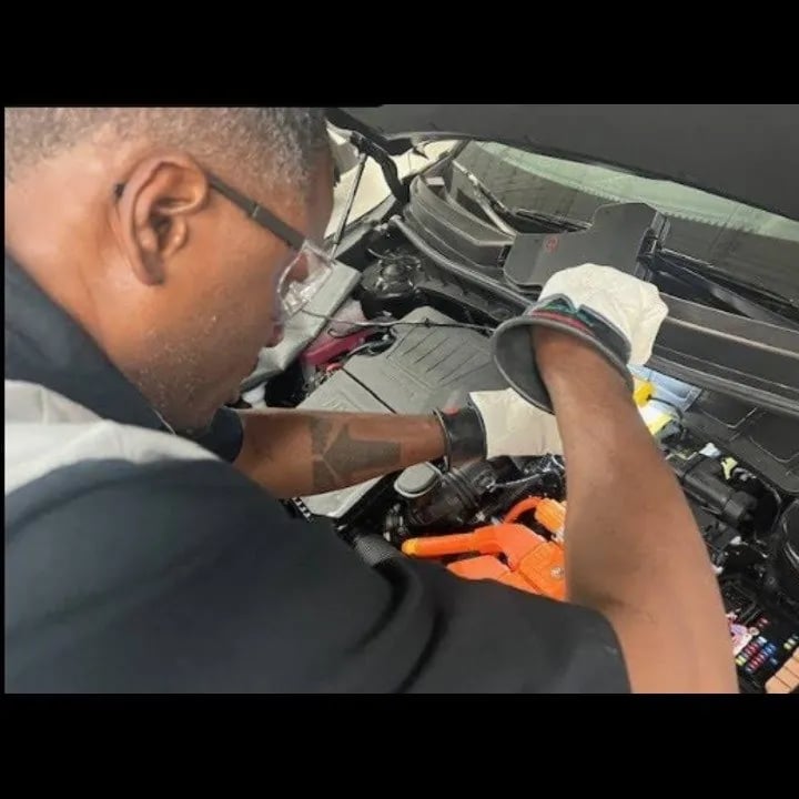 Mobile mechanic working safely beside a passenger vehicle in a driveway