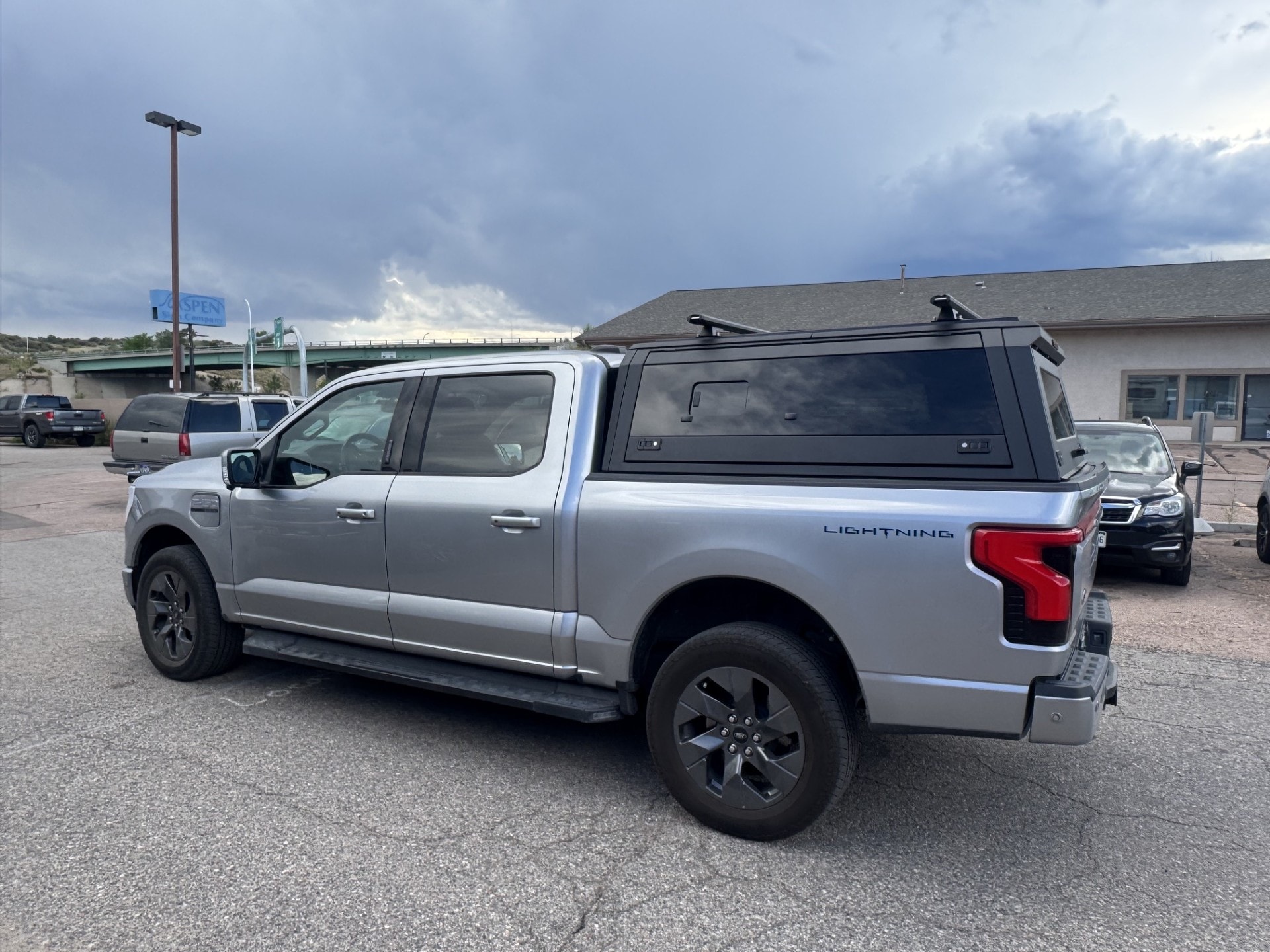 Silver Ford F-150 Lightning with a black aluminum truck cap and roof bars