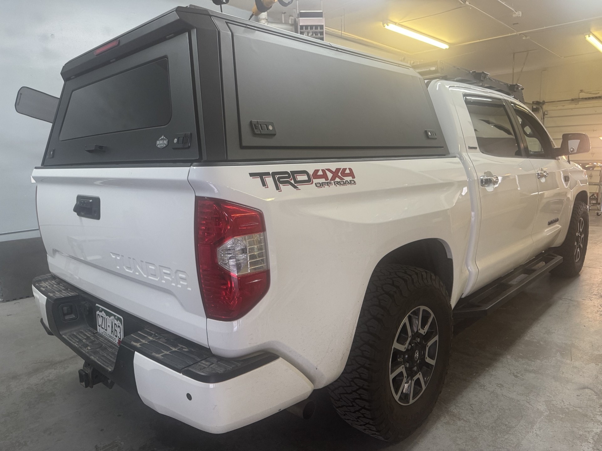 White Toyota Tundra with a black aluminum truck cap