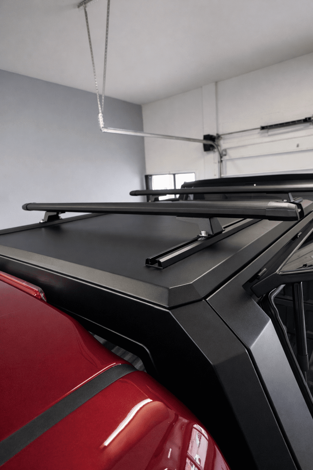 Roof rack crossbars installed on a black aluminum truck topper