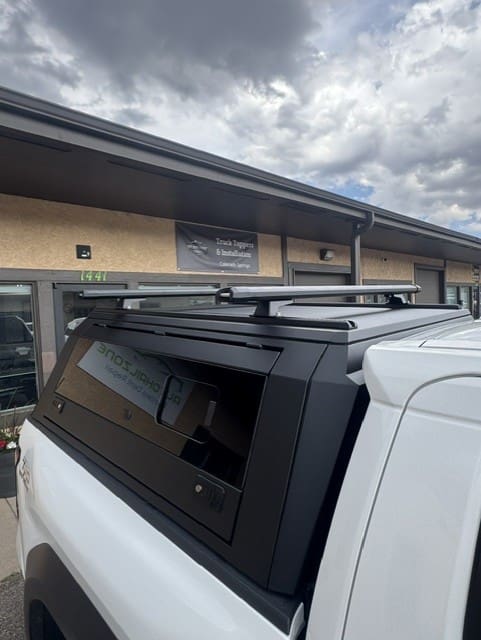 Toyota Tacoma with a black aluminum topper viewed from the side